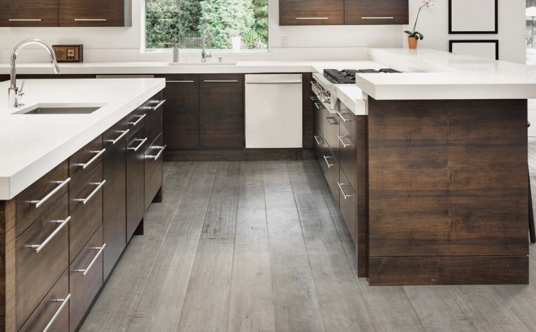 A kitchen with wooden cabinets , white counter tops , and a large island.