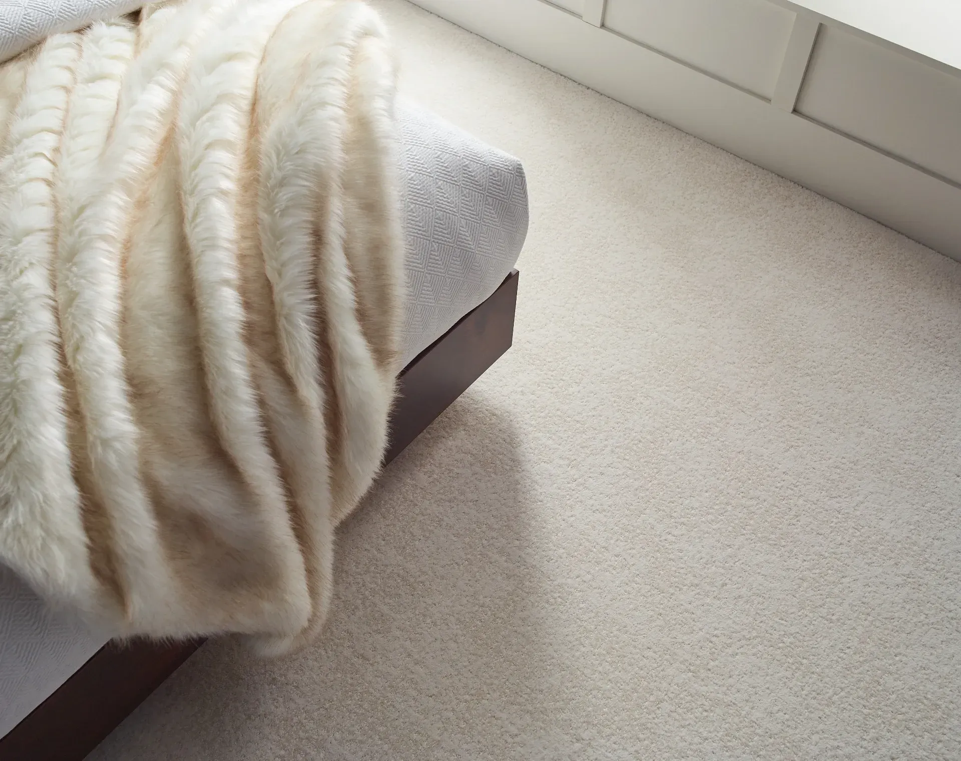 A bed with a white fur blanket on top of it