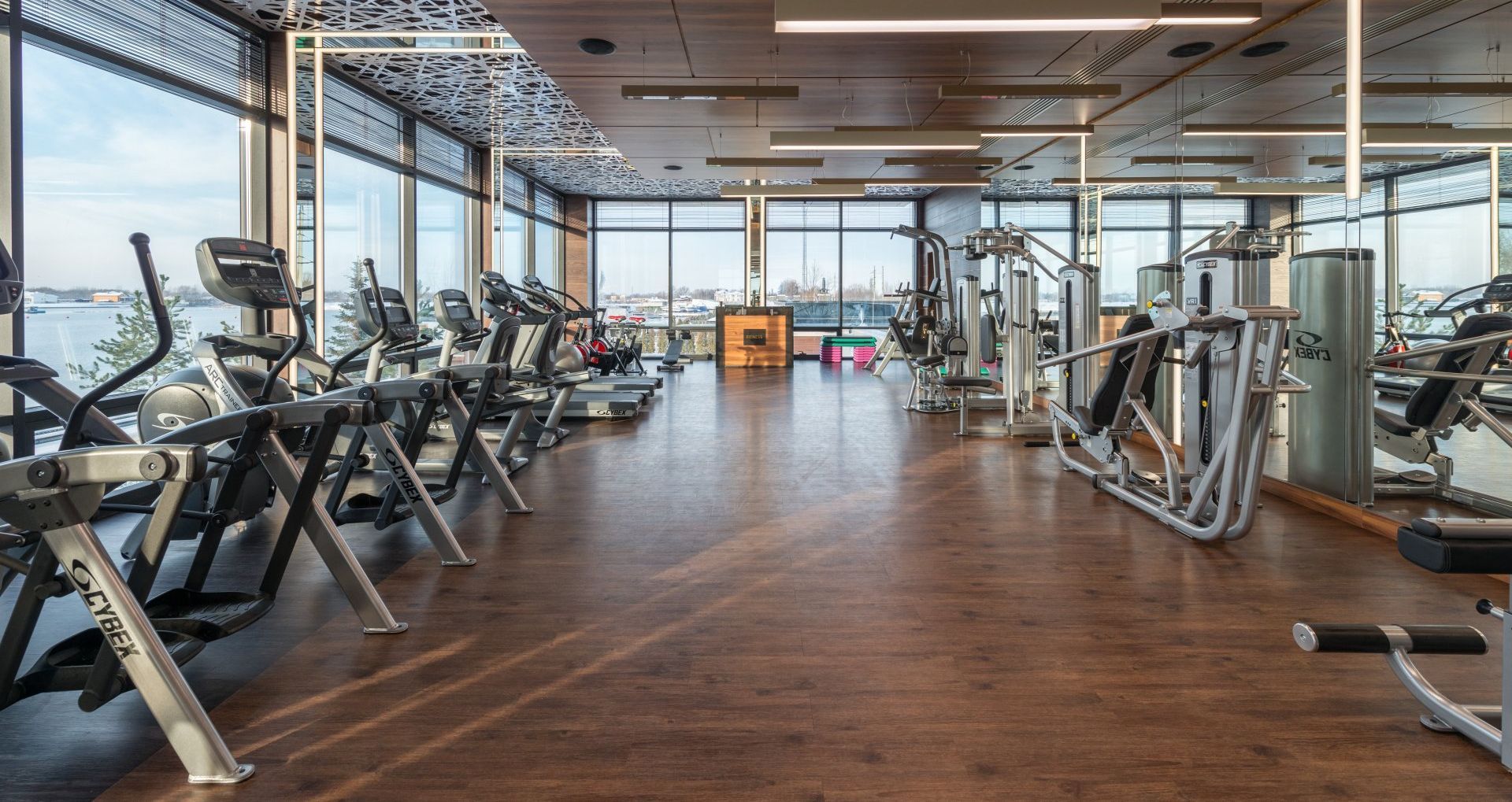 An empty gym with a lot of exercise equipment and a lot of windows.