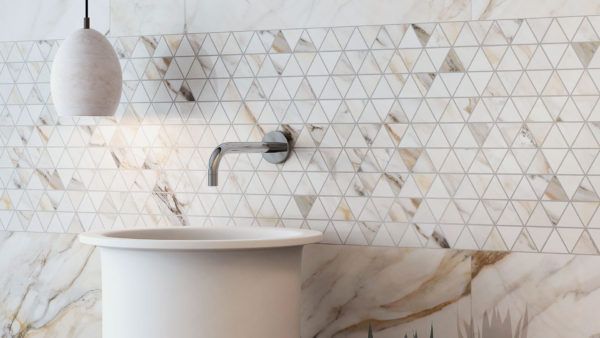 A bathroom with a sink and a marble wall.