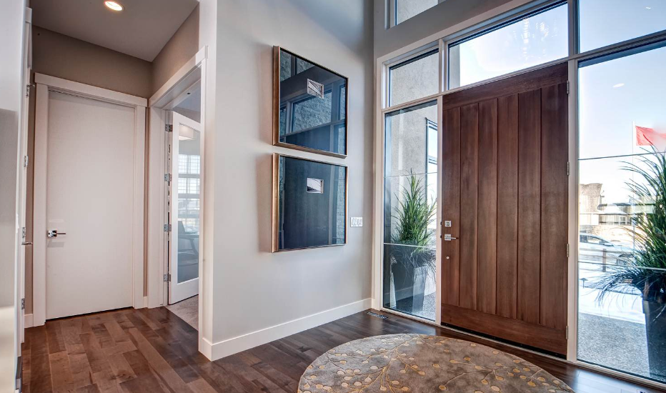 A hallway in a house with a wooden door and a rug.
