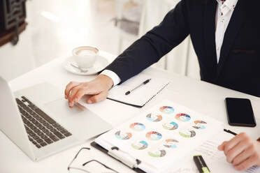 A man is sitting at a desk with a laptop and a cup of coffee.