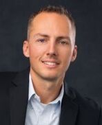 A man in a suit and white shirt is smiling for the camera.