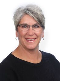 A woman wearing glasses and earrings is smiling for the camera.