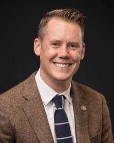 A man in a suit and tie is smiling for the camera.