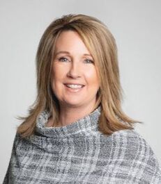 A woman in a plaid sweater is smiling for the camera.
