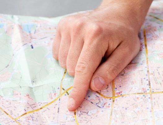 A person is pointing at a map with their finger.