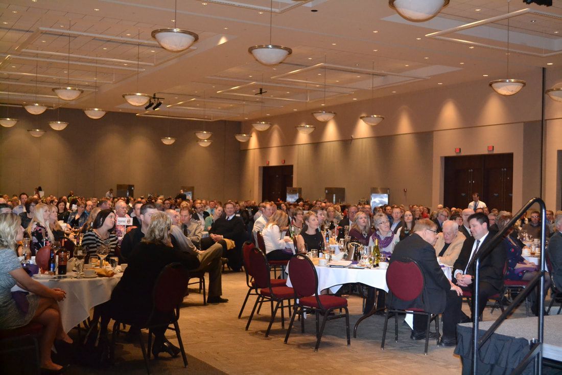 A large room filled with people sitting at tables and chairs