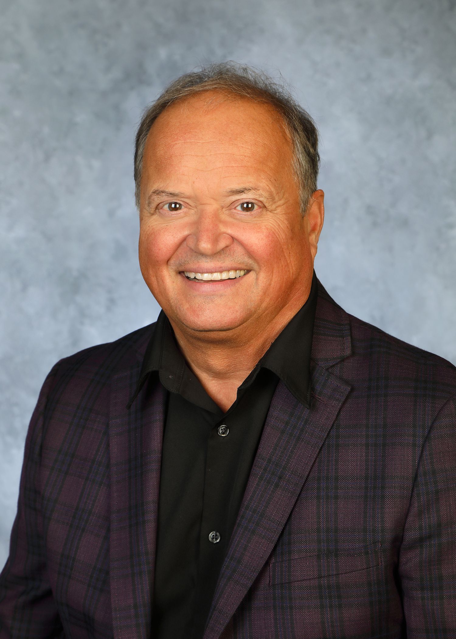 A man in a suit and tie is smiling for the camera.