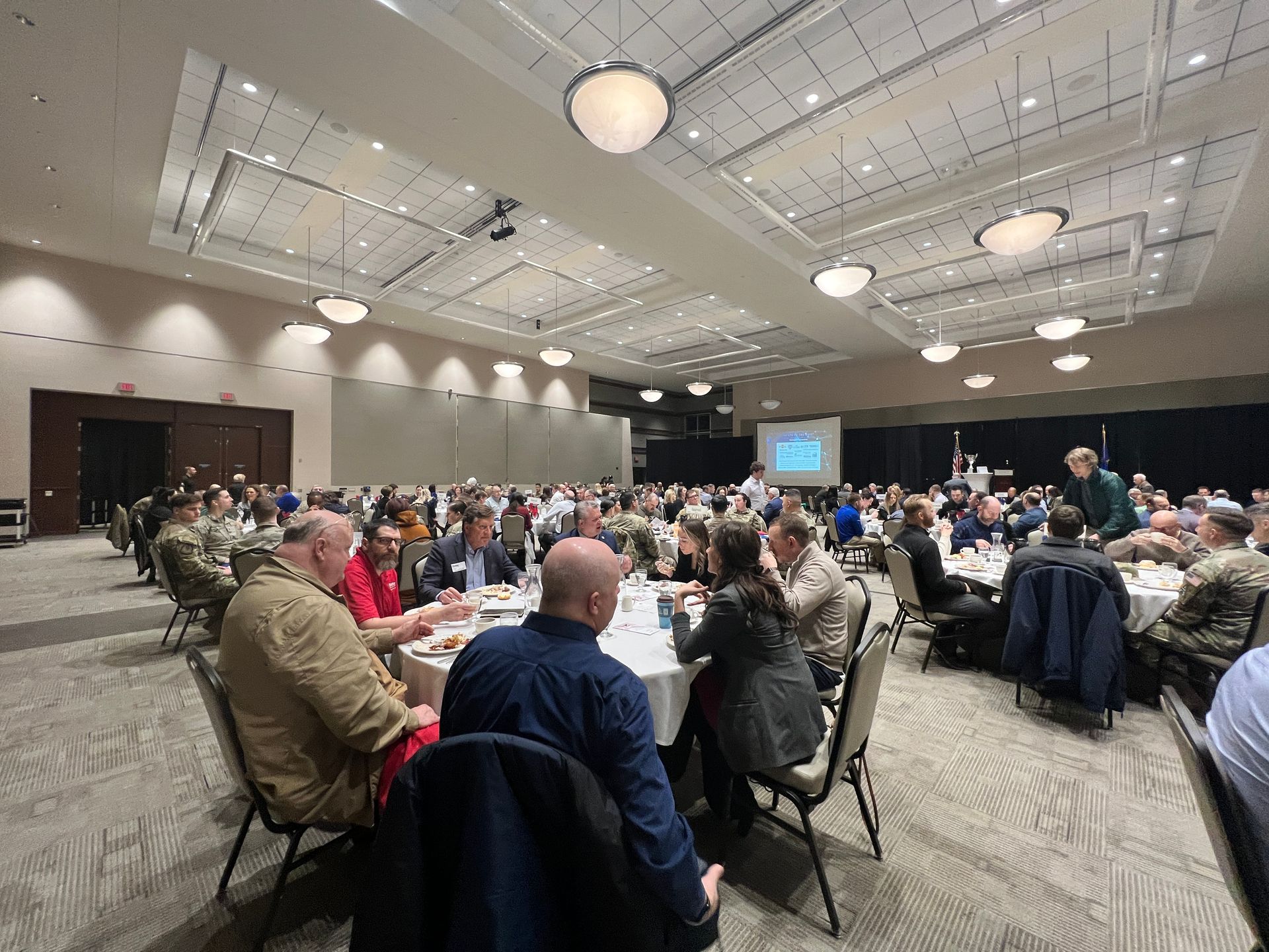 A large group of people are sitting at tables in a large room.
