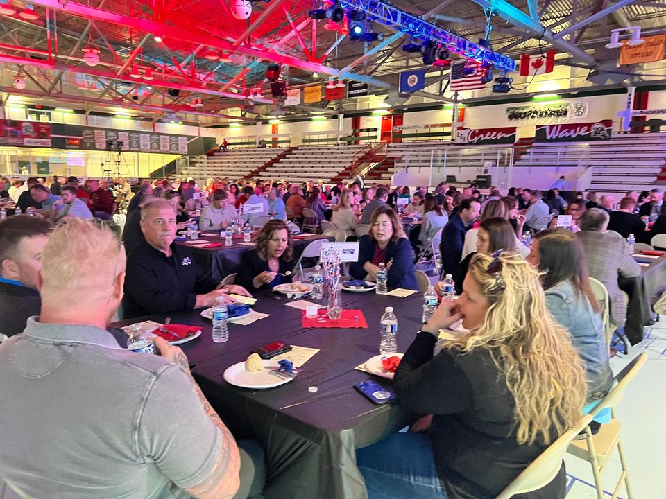 A large group of people are sitting at tables in a stadium.