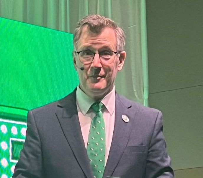 A man in a suit and tie is standing in front of a green screen.