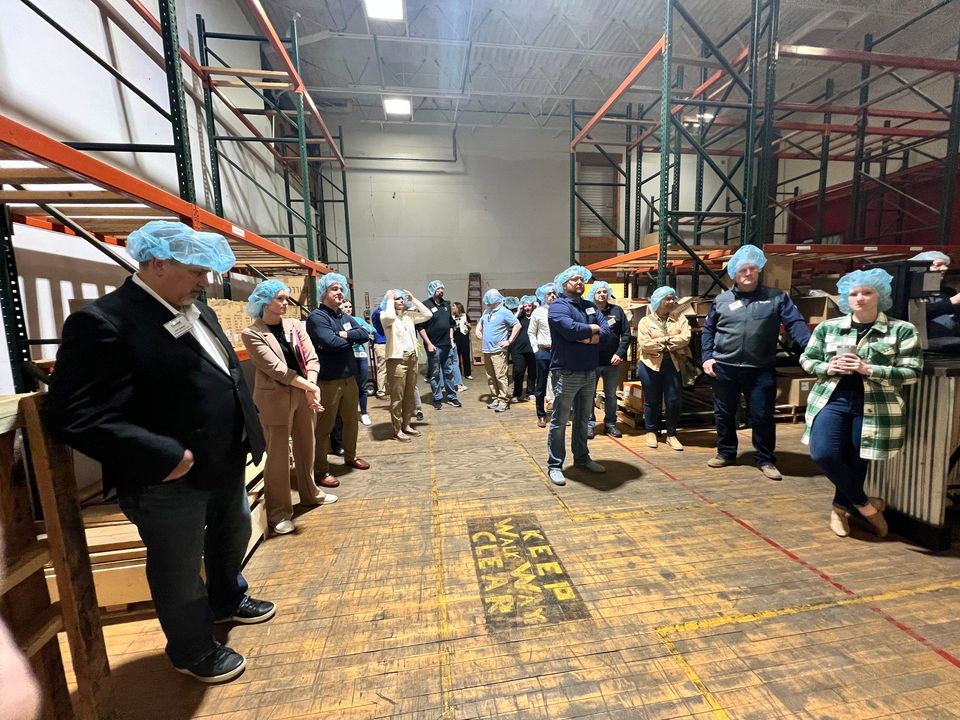 A group of people wearing blue hats are standing in a warehouse.