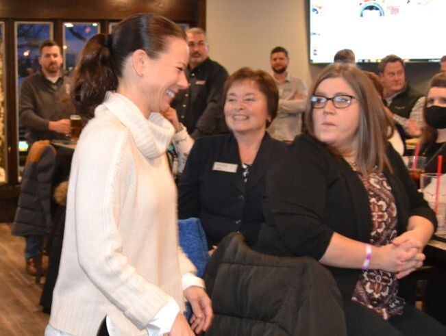 A woman in a white sweater is talking to two other women