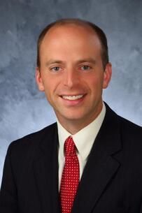 A man in a suit and tie is smiling for the camera