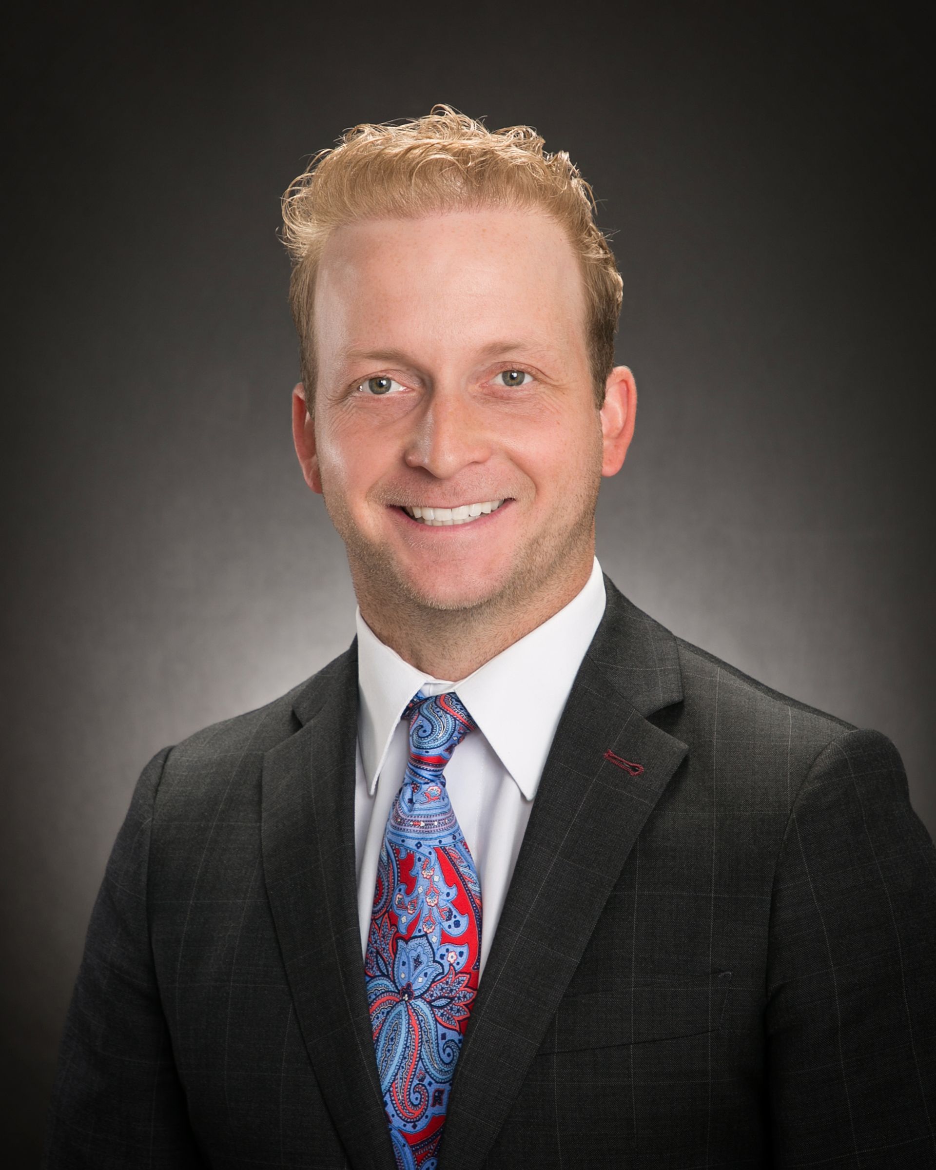 A man in a suit and tie is smiling for the camera.