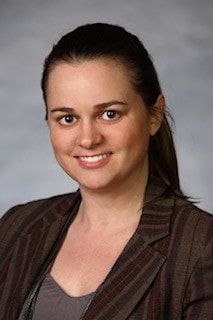 A woman in a brown jacket is smiling for the camera.