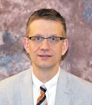 A man in a suit and tie is smiling for the camera.