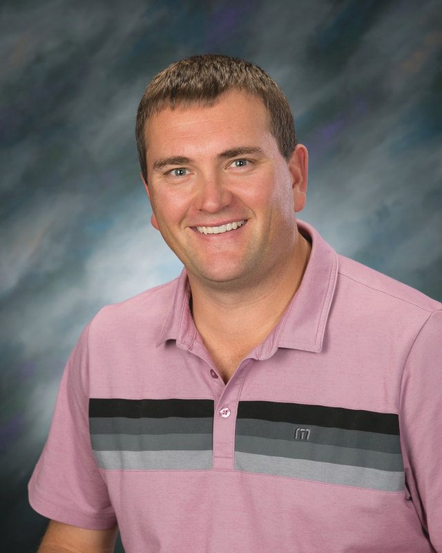 A man in a pink shirt is smiling for the camera.