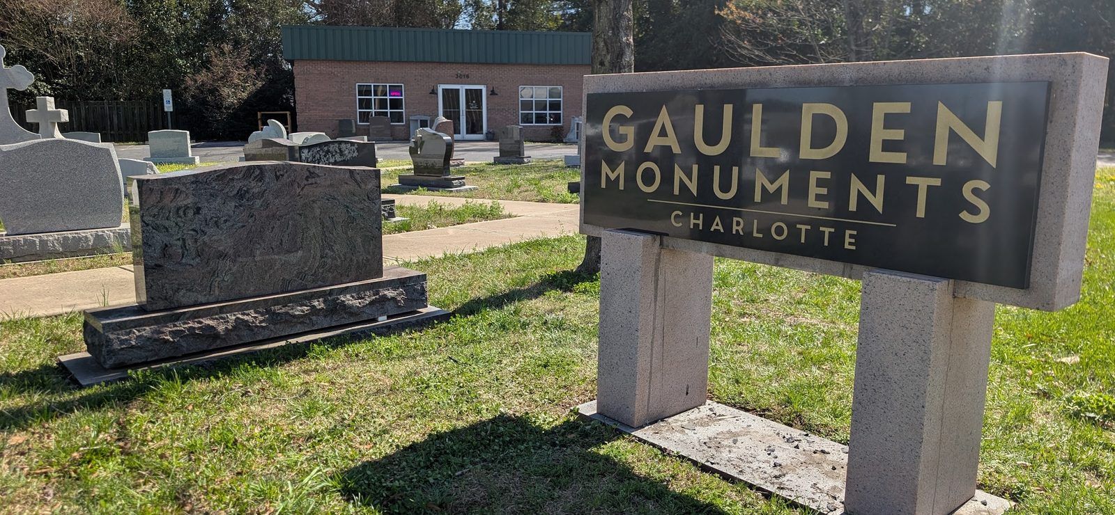 The Gaulden Monuments Charlotte granite sign in the display yard at 3016 N Graham St, with the showroom building behind it