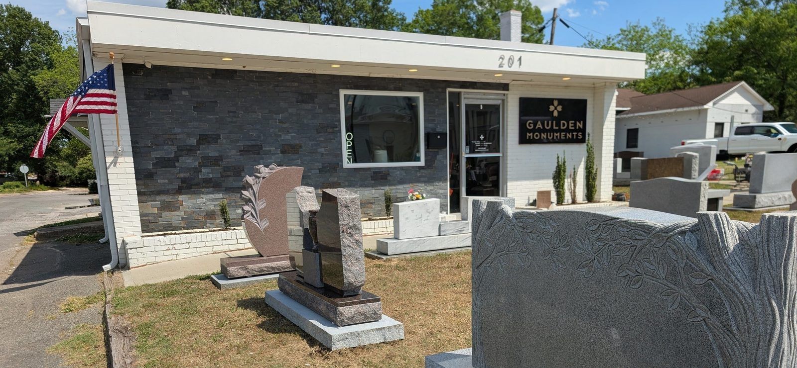 The Gaulden Monuments Monroe showroom at 201 S Main St, with the Gaulden Monuments sign on the building and finished monuments across the front