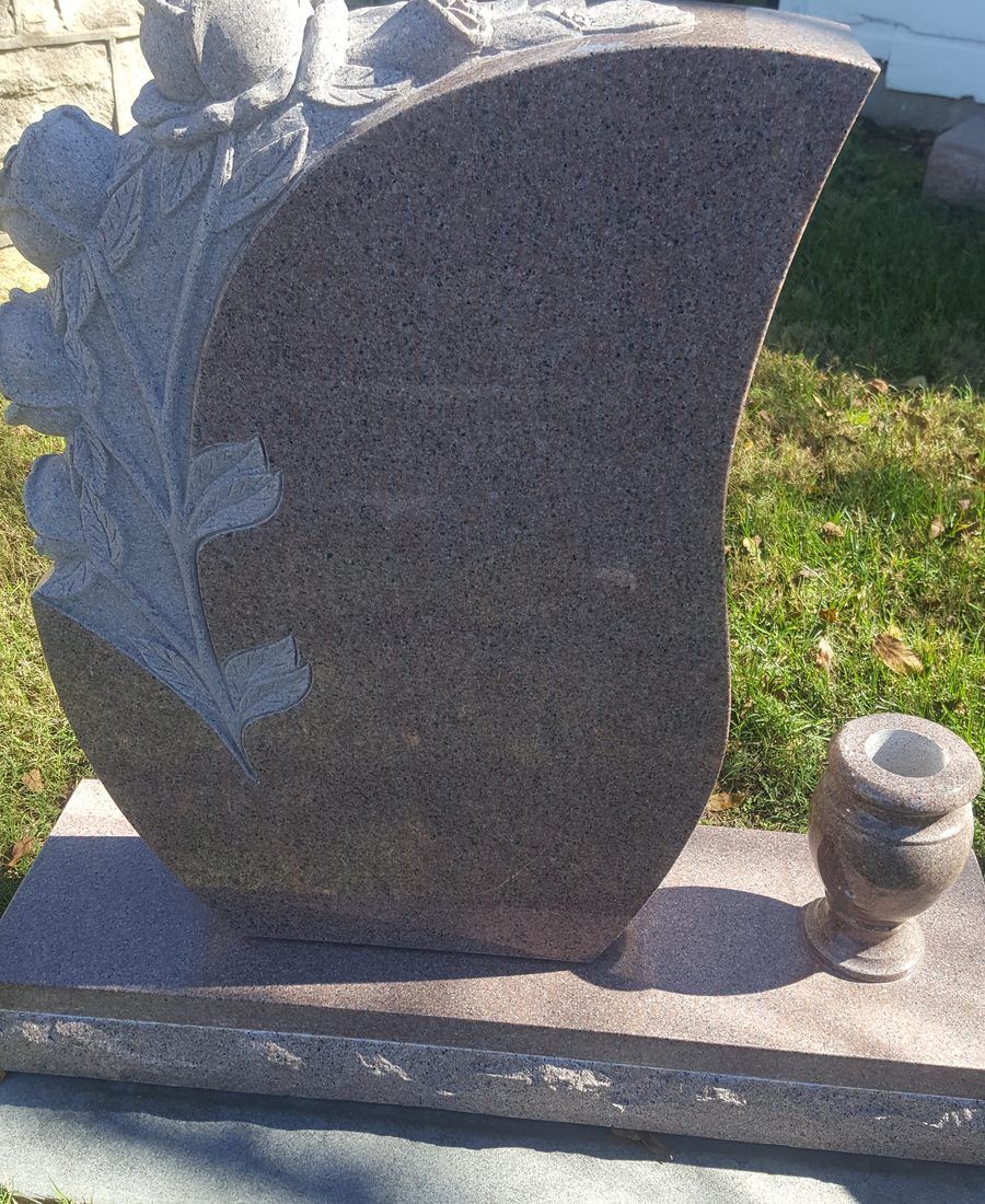 A rose carved in relief into the face of a mauve granite monument