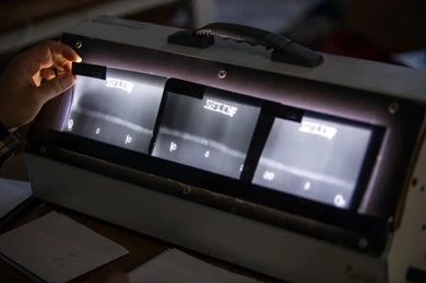 una persona sostiene un trozo de papel frente a una máquina.