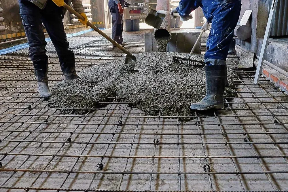 Workers Pour Wet Concrete Over Steel Rebar at A Construction Site — Kempsey Concrete Contractors PTY LTD In Nambucca Heads, NSW