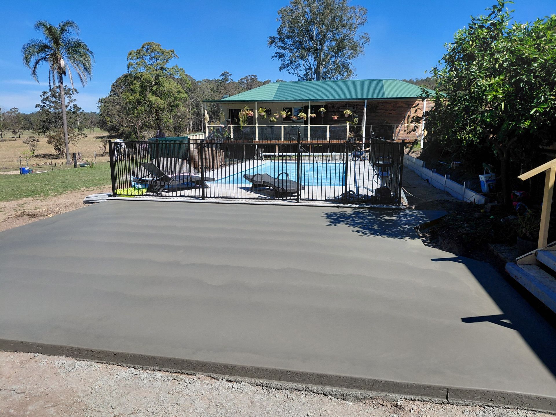 Backyard Pool with A Concrete Patio, Metal Fence, and Green-Roofed Gazebo in The Background — Kempsey Concrete Contractors PTY LTD In Nambucca Heads, NSW