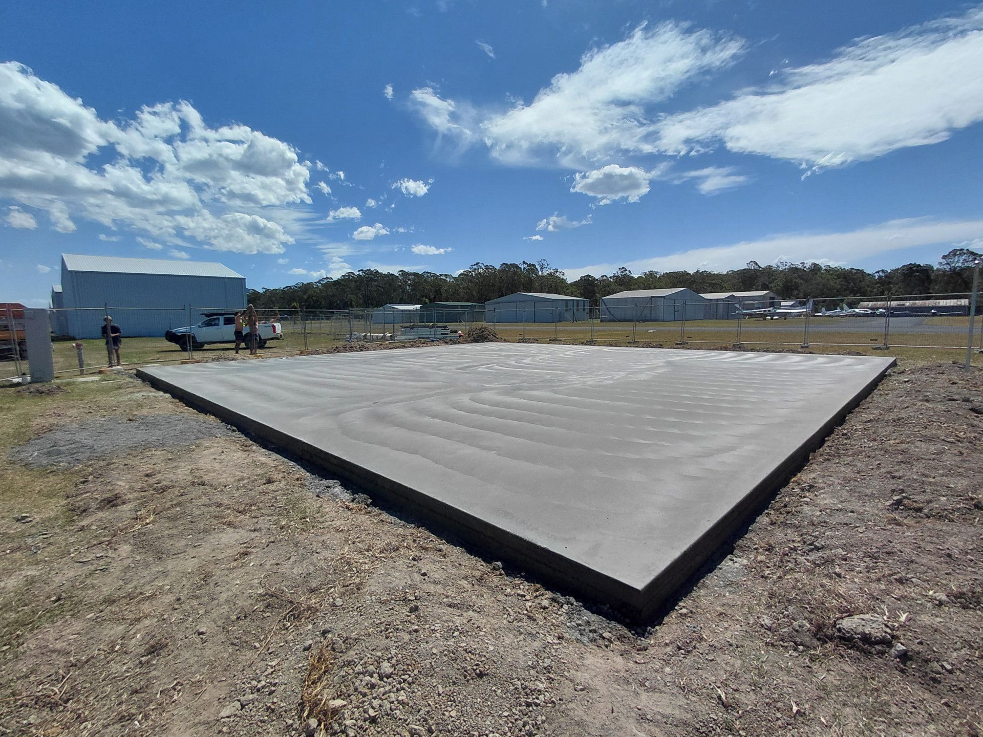 Concrete Slab Foundation in An Open Dirt Lot Under a Cloudy Blue Sky — Kempsey Concrete Contractors PTY LTD In Dondingalong, NSW