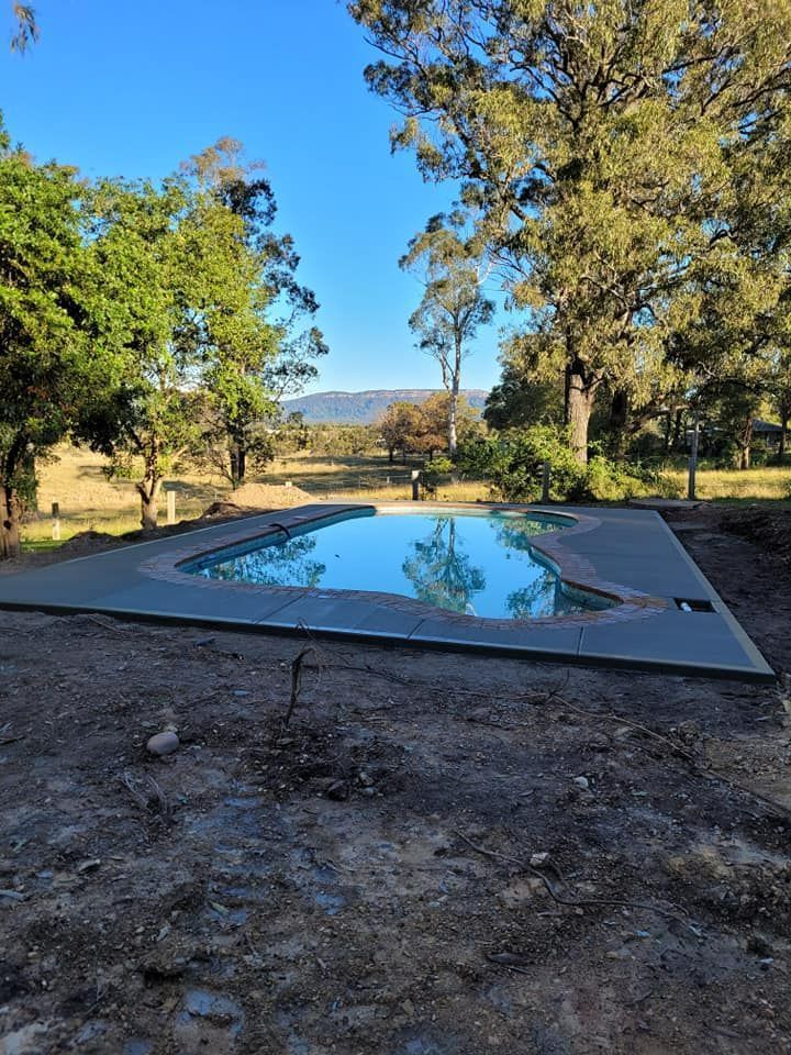 Oval Backyard Pool with Blue Water, Surrounded by Trees and A Countryside View — Kempsey Concrete Contractors PTY LTD In Dondingalong, NSW