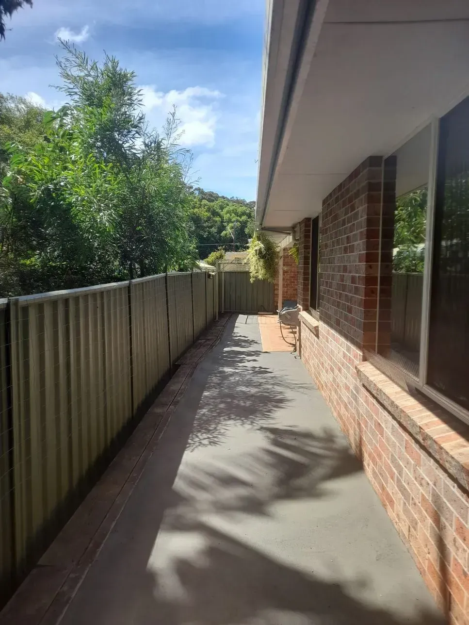 Narrow Side Walkway Beside a Brick House, with A Fence — Kempsey Concrete Contractors PTY LTD In Dondingalong, NSW