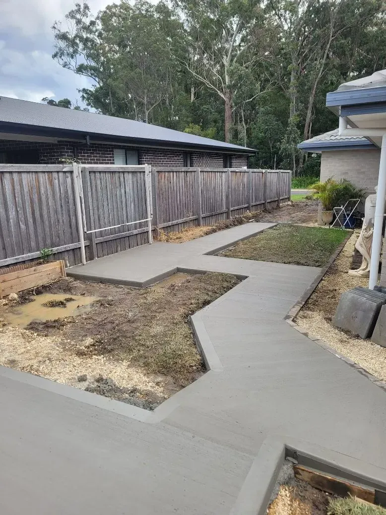 Concrete Garden Pathway Beside a Wooden Fence and House — Kempsey Concrete Contractors PTY LTD In Dondingalong, NSW