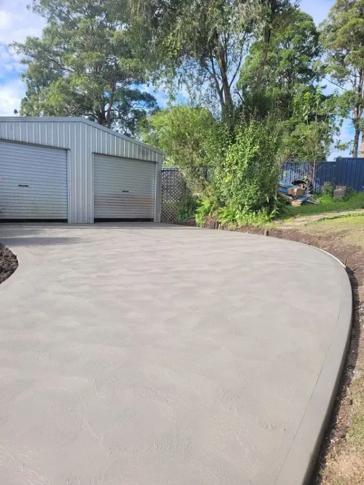 Curved Concrete Driveway Beside a Metal Shed — Kempsey Concrete Contractors PTY LTD In Dondingalong, NSW