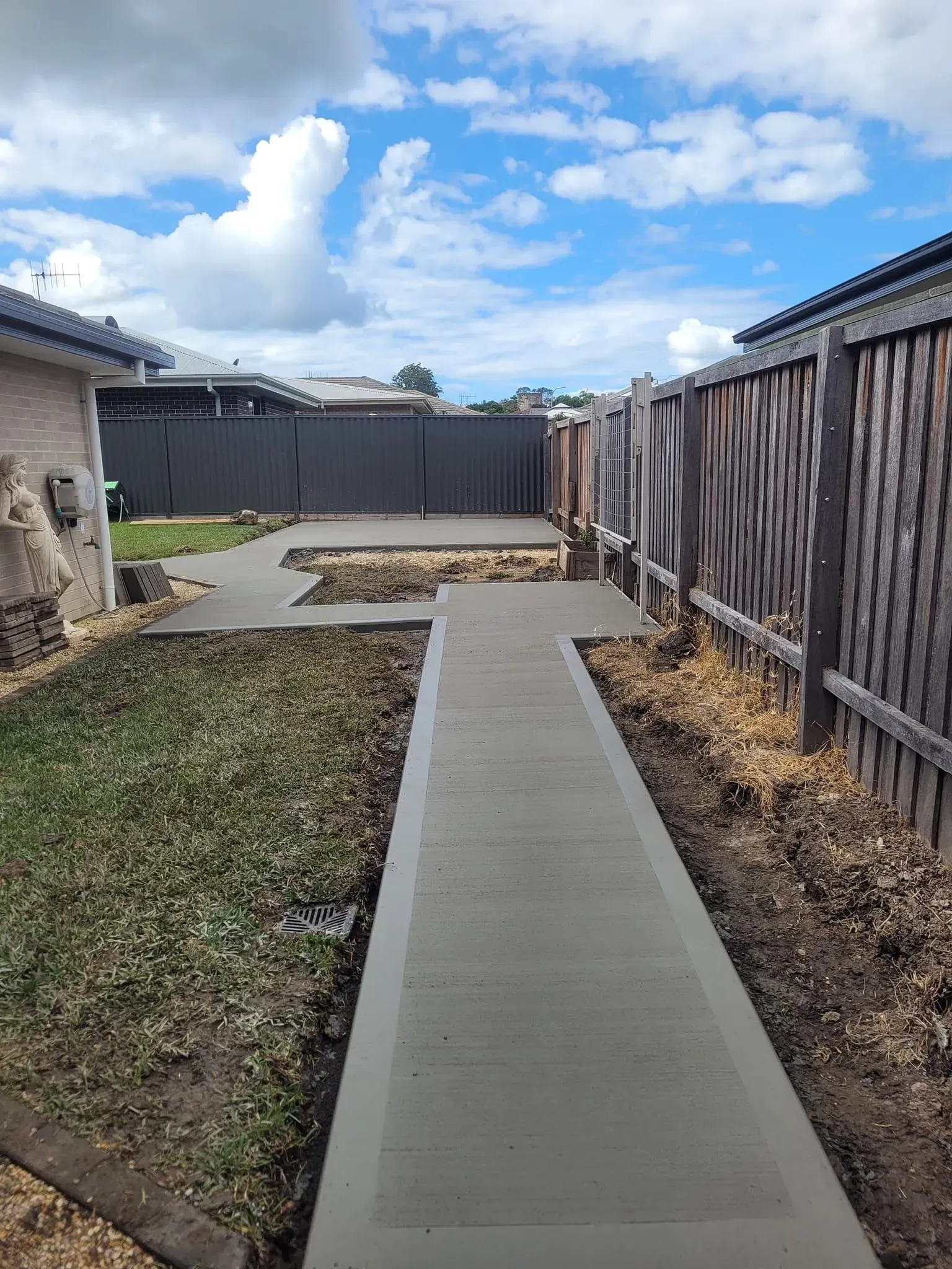 Concrete Walkway Between a House and Wooden Fence — Kempsey Concrete Contractors PTY LTD In Dondingalong, NSW