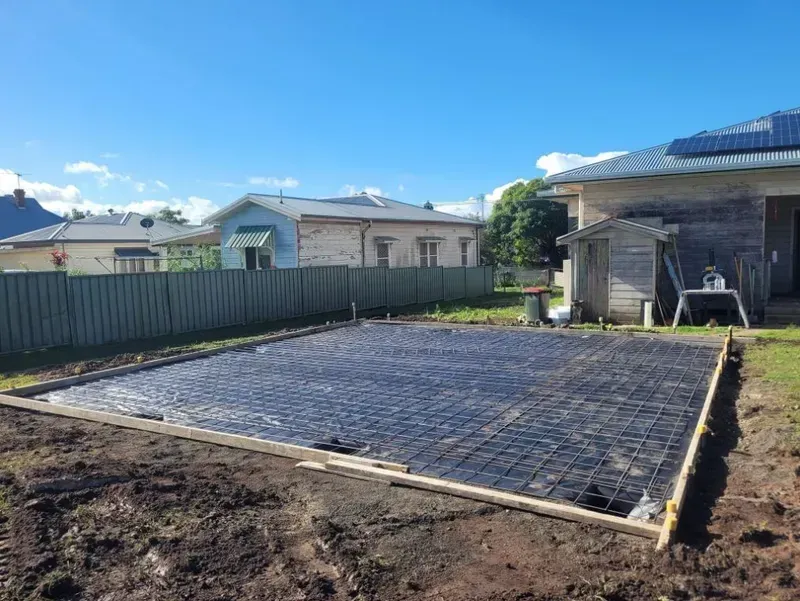 Backyard Construction Site with A Freshly Laid Rectangular Concrete Slab — Kempsey Concrete Contractors PTY LTD In Dondingalong, NSW