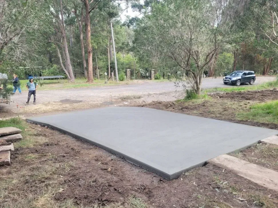 Concrete Slab in A Wooded Park Area, with A Car Parked Nearby and Two People in The Distance — Kempsey Concrete Contractors PTY LTD In Dondingalong, NSW