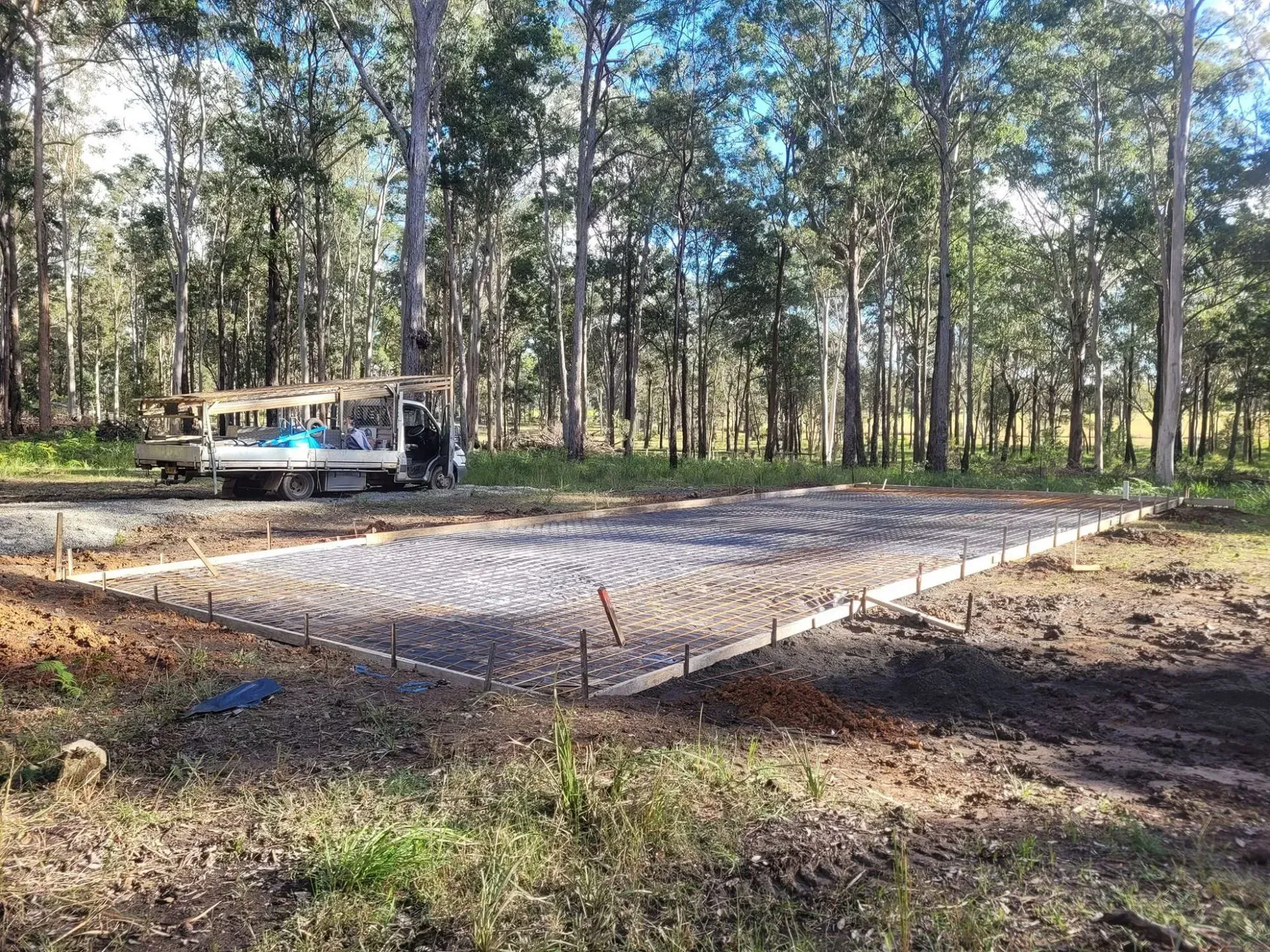 Concrete Slab Foundation in A Wooded Lot with A Bus Parked Nearby — Kempsey Concrete Contractors PTY LTD In Dondingalong, NSW