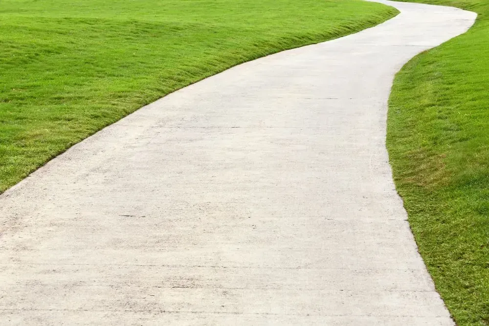 Curved White Pathway Winding Through Bright Green Grass — Kempsey Concrete Contractors PTY LTD In Port Macquarie, NSW
