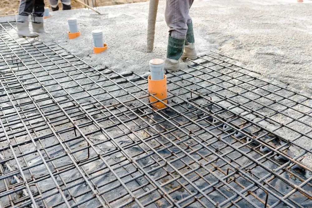 Workers Placing Concrete Over a Rebar Grid with Orange Spacers — Kempsey Concrete Contractors PTY LTD In Nambucca Heads, NSW