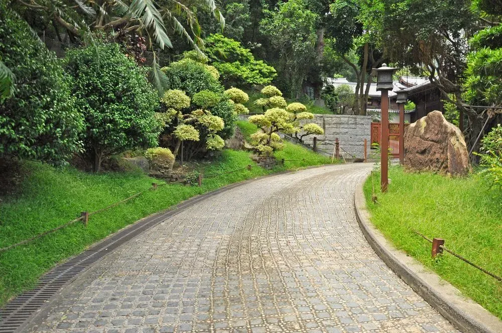 Curving Cobblestone Path Through Lush Green Garden — Kempsey Concrete Contractors PTY LTD In Port Macquarie, NSW