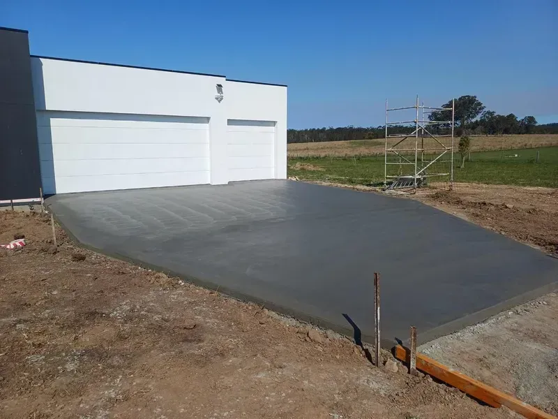 Concrete Driveway Leading to A White Garage Building on A Rural Lot — Kempsey Concrete Contractors PTY LTD In Macksville, NSW