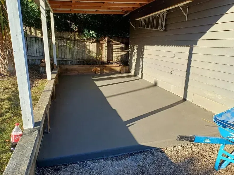 Freshly Poured Concrete Slab Under a Covered Patio Beside a Gray House — Kempsey Concrete Contractors PTY LTD In Macksville, NSW