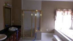 Empty room with beige walls, mirrored closet doors, a sink, and a bright window with curtains.