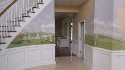 Indoor staircase with painted mural walls, white wainscoting, and a doorway leading to a hall