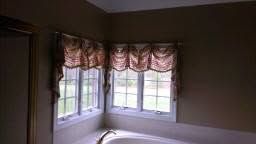 Corner bedroom with three windows, pink valances, and a white bed frame