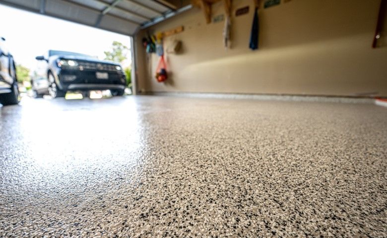 Garage floor with a black truck parked near the open door, seen from a low angle.