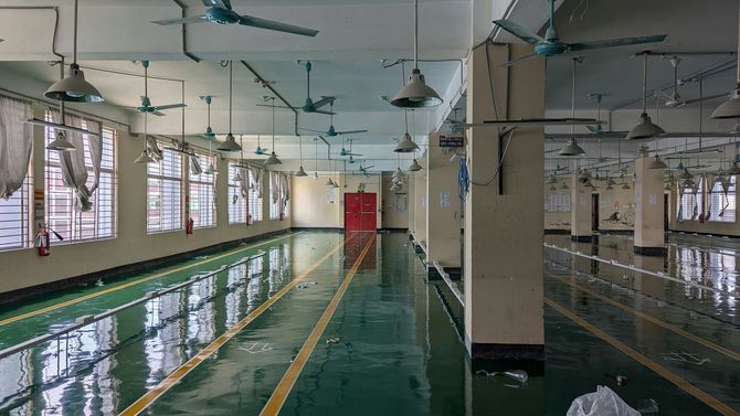 Indoor swimming pool with lanes, ceiling fans, and large windows, seen from the deck.