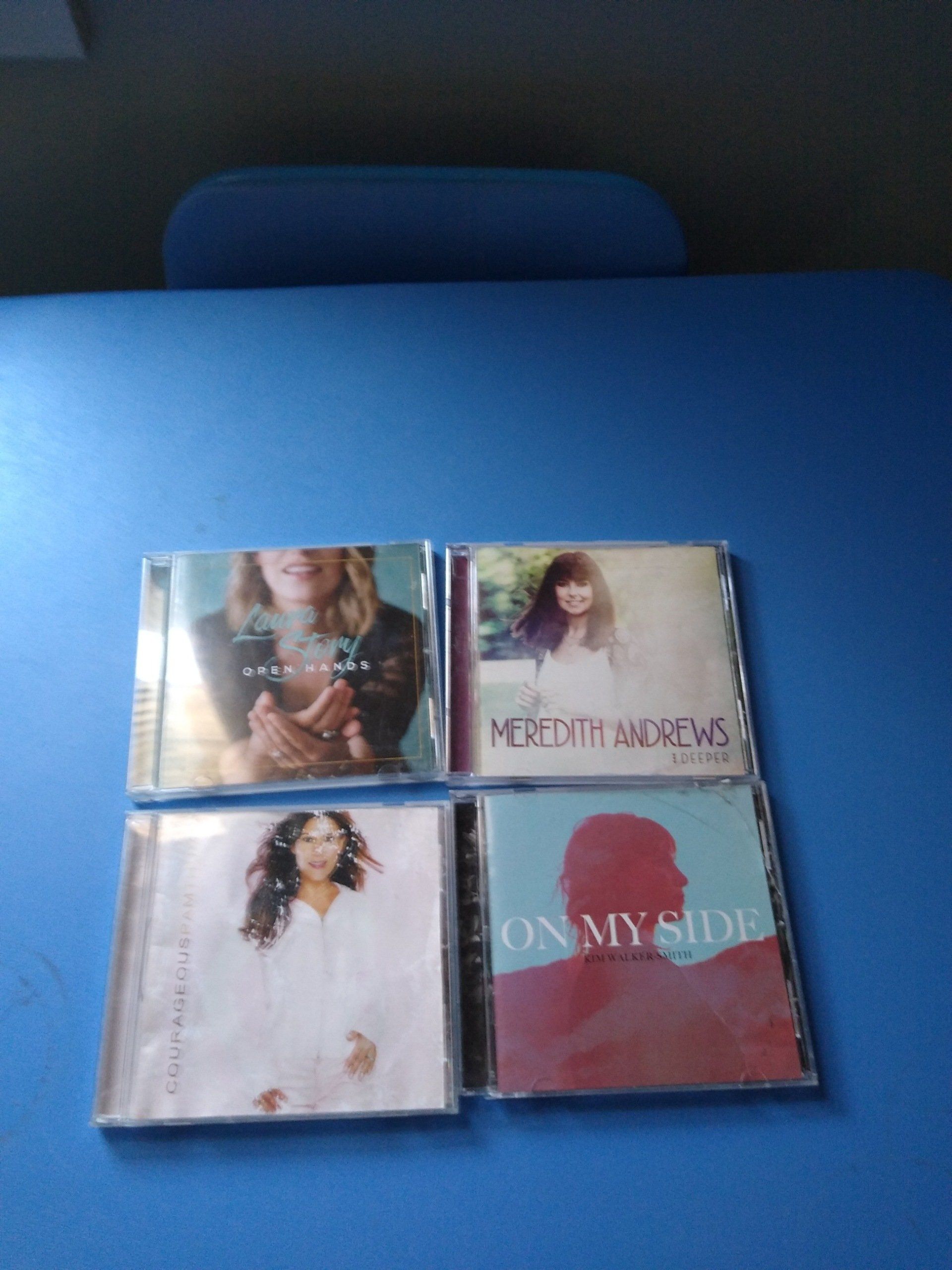 Four CDs on a blue surface, featuring album artwork.