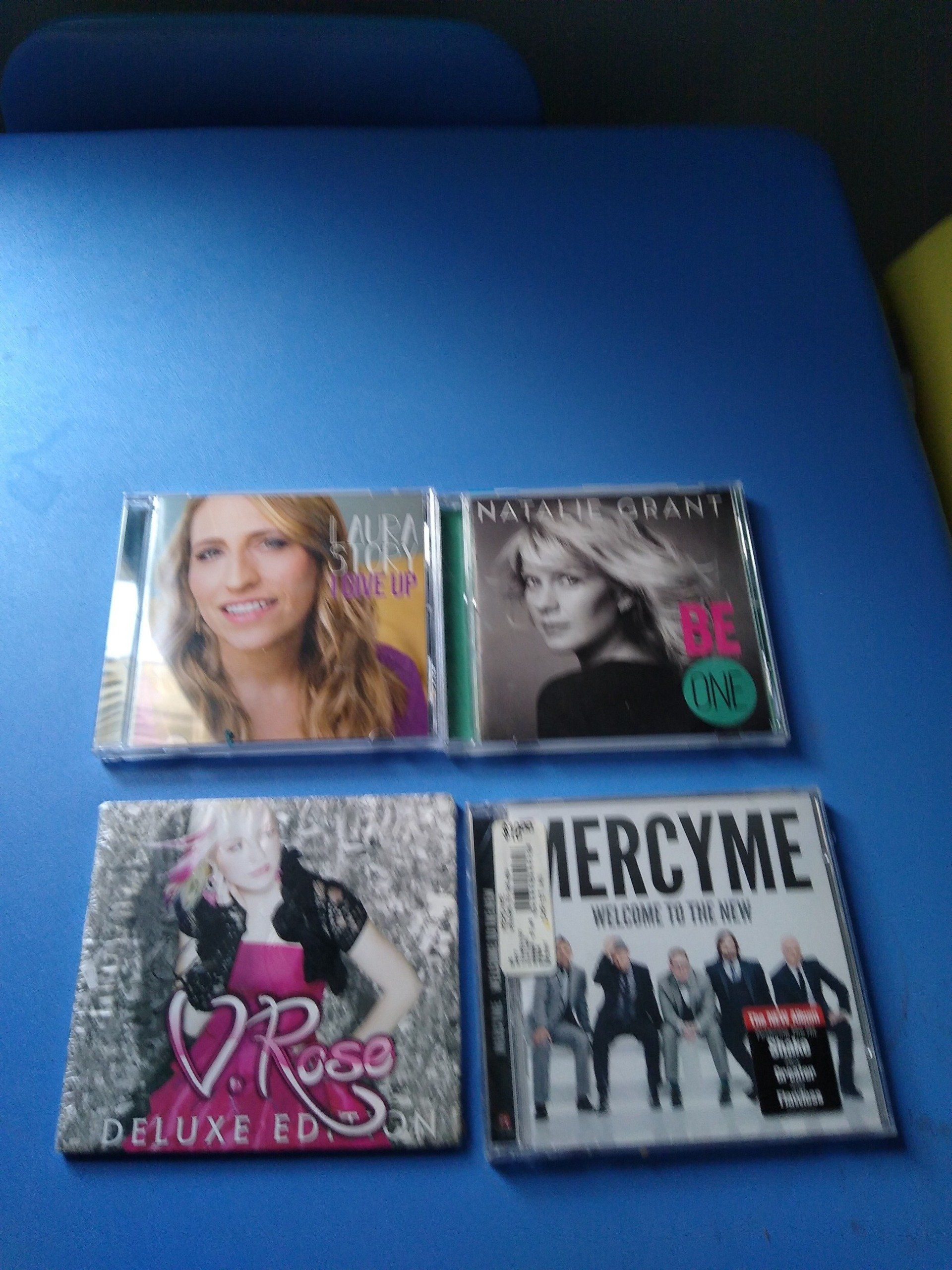 Four music CDs on a blue surface:  Natalie Grant, D. Rosa, MercyMe, and a blonde woman.